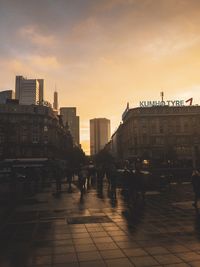 People walking on street amidst buildings in city against sky