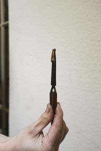Close-up of hand holding knife against wall