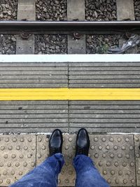 Low section of man standing on railroad station platform