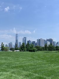 Scenic view of field by buildings against sky