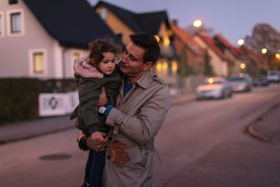 Father looking at sad daughter while standing outdoors during sunset