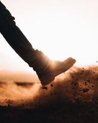 Low section of person on sand against clear sky