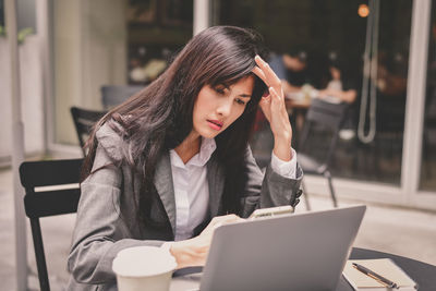 Businesswoman using mobile phone while sitting at table in cafe