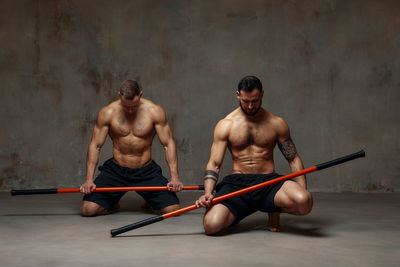 Men holding combat stick in gym