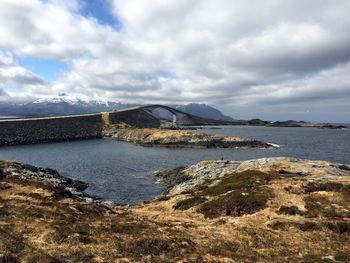 Arch bridge over sea against cloudy sky