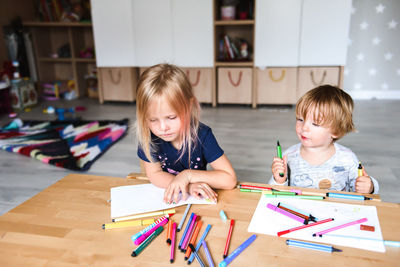 Little boy with sister drawing with felt-tip pens