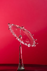 Close-up of red light bulb over white background