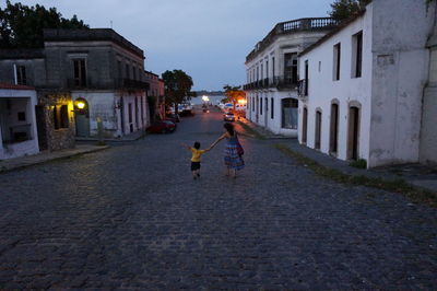 People walking on pathway along buildings at night