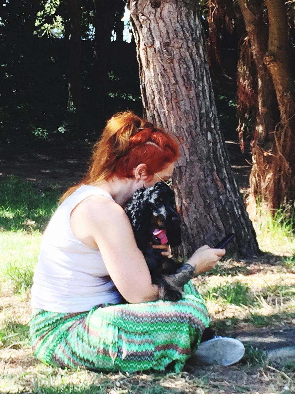 YOUNG WOMAN SITTING ON TREE TRUNK