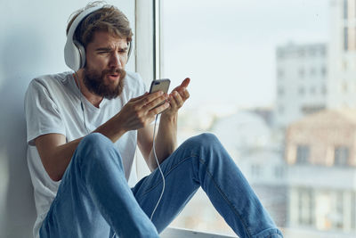 Side view of young man using mobile phone