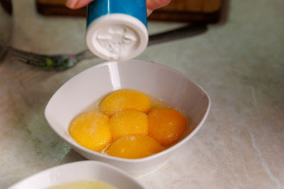 Process of salting five raw chicken egg yolks in a white ceramic bowl