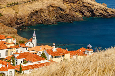 High angle view of houses by sea against buildings