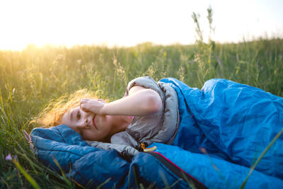 Cute girl in sleeping bag on field