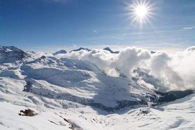 Ski resort la plagne in french alps - scenic view of snowcapped mountains above clouds with sunbeams