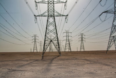 Electricity pylons on landscape against clear sky