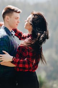 Side view of young couple standing face to face in forest