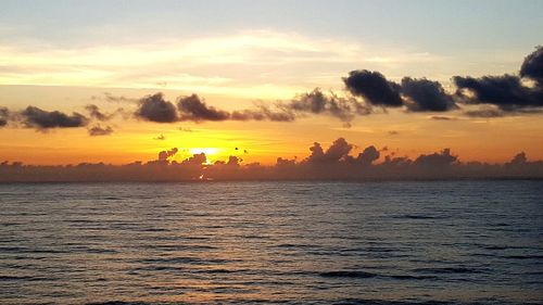 Scenic view of sea against dramatic sky during sunset