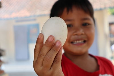 Close-up portrait of smiling boy holding egg 
