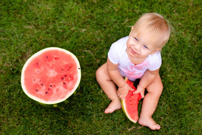 High angle view of boy holding fruit on grass