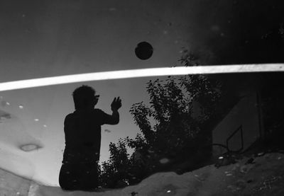 Silhouette man playing with ball in background