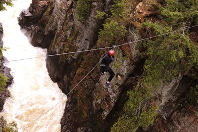 Full length of man zip line over river