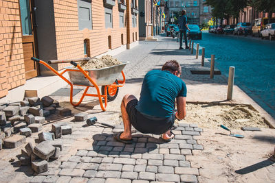 Rear view of man sitting on sidewalk