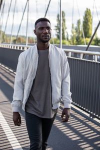 Portrait of young man standing on footbridge