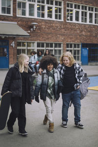 Happy friends talking to each other while walking in school campus