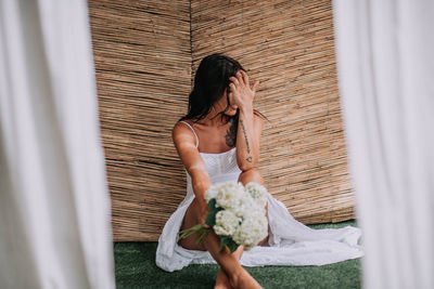 Midsection of woman holding umbrella while standing against white curtain