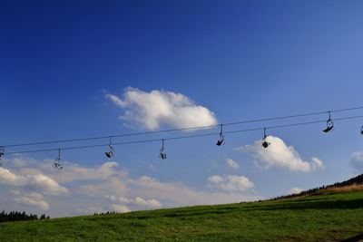 Low angle view of ski lift over field against sky