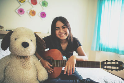 Portrait of smiling woman sitting on bed at home