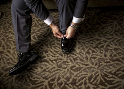 Low section of businessman tying shoelace on carpet