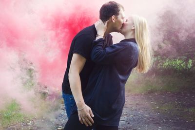 Side view of young couple kissing amidst smoke
