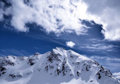 Low angle view of snowcapped mountains against cloudy sky