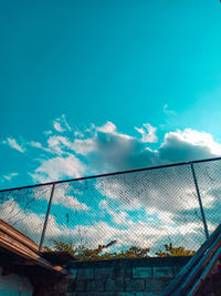 Low angle view of blue sky seen through chainlink fence