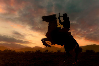 Silhouette man riding horse against sky during sunset