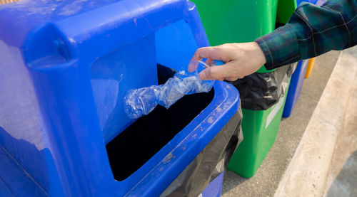 People hand throwing empty water bottle in recycle bin. blue plastic recycle bin. man discard water