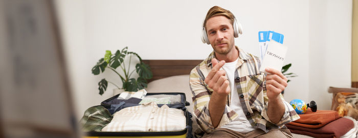 Portrait of young man using mobile phone while sitting at home