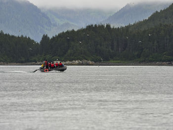 People rafting on river against mountains