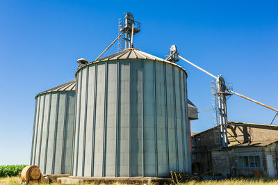 Low angle view of water tower against clear blue sky