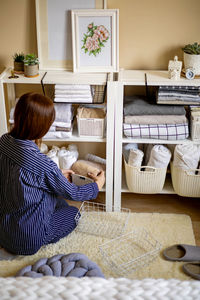 Rear view of woman organizing clothes at home