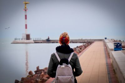 Rear view of woman standing by sea against clear sky