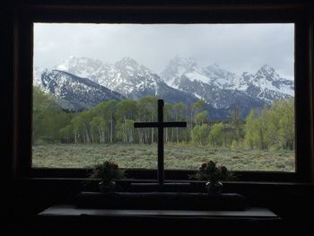 View of cross on landscape through window