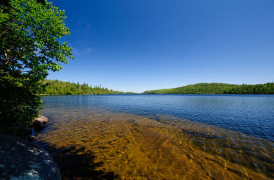 Scenic view of lake against clear blue sky