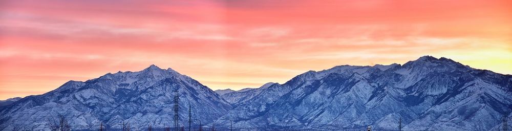 Scenic view of snowcapped mountains against orange sky