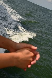 Midsection of person hand on sea shore
