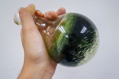 Close-up of hand holding glass over white background