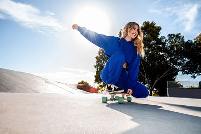 Cheerful caucasian woman with blonde hair skating in urban setting