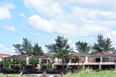 Houses by trees against sky