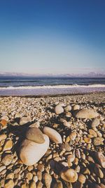 Stones on beach against clear sky